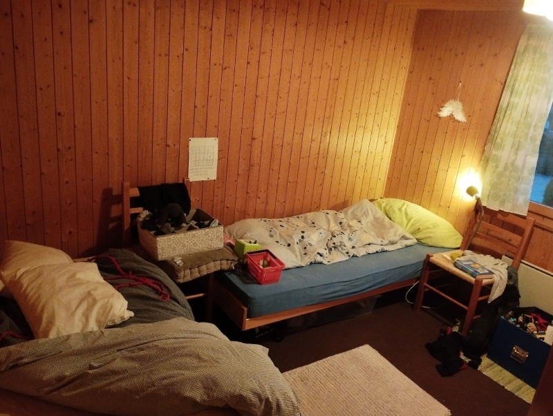 In einem schlichten Holzschlafraum in Liedertswil weist die unruhige Bettsituation auf moegliche Bettwanzen hin, weshalb ein Kammerjaeger noetig sein koennte.