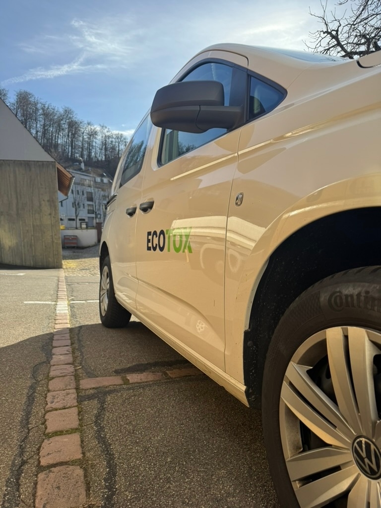 Ein Kammerjaegerfahrzeug steht in Liedertswil seitlich im Sonnenlicht auf einem gepflasterten Parkplatz, waehrend die Umgebung mit Haeusern und Baumbestand im Hintergrund sichtbar ist.